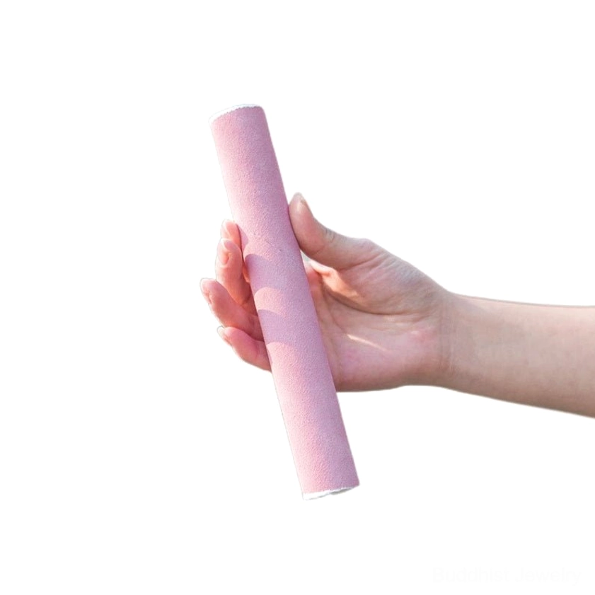Pink leather striker mallet for singing bowl shown with hand for scale on white background