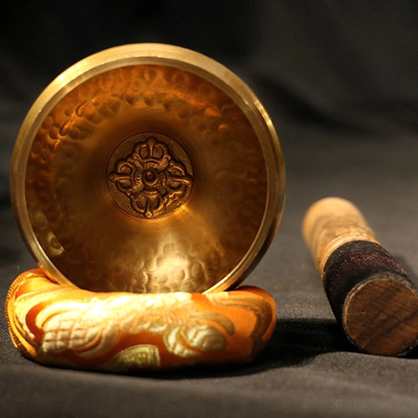 Authentic Buddhist meditation singing bowl with central vajra emblem, embroidered silk base, and wooden mallet for sound healing practice