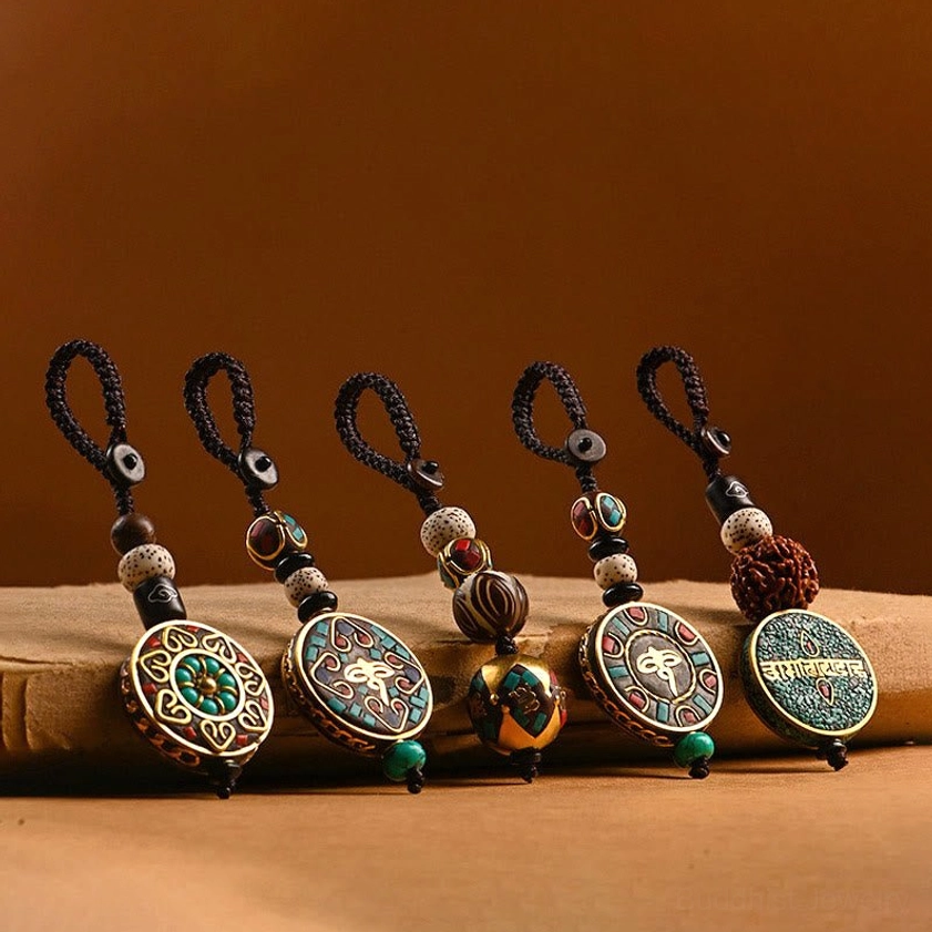 Collection of Buddhist keychains with assorted sacred symbols and patterns, displayed on wooden board