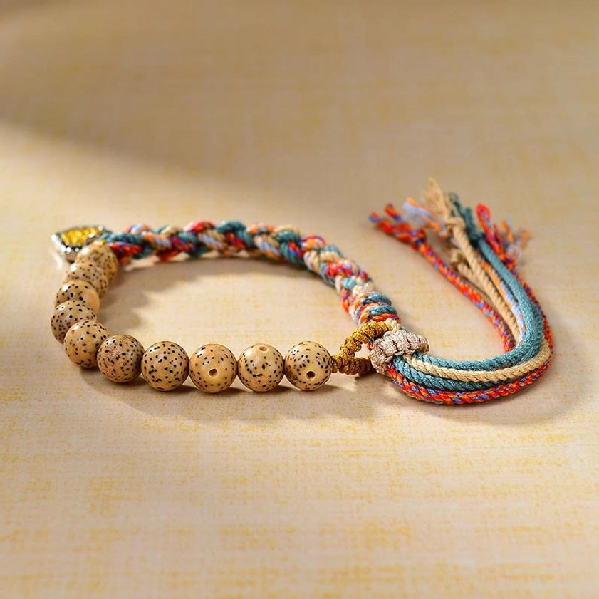 Handcrafted Buddhist protection bracelet with braided colored rope and natural bodhi seed beads, flat lay side view