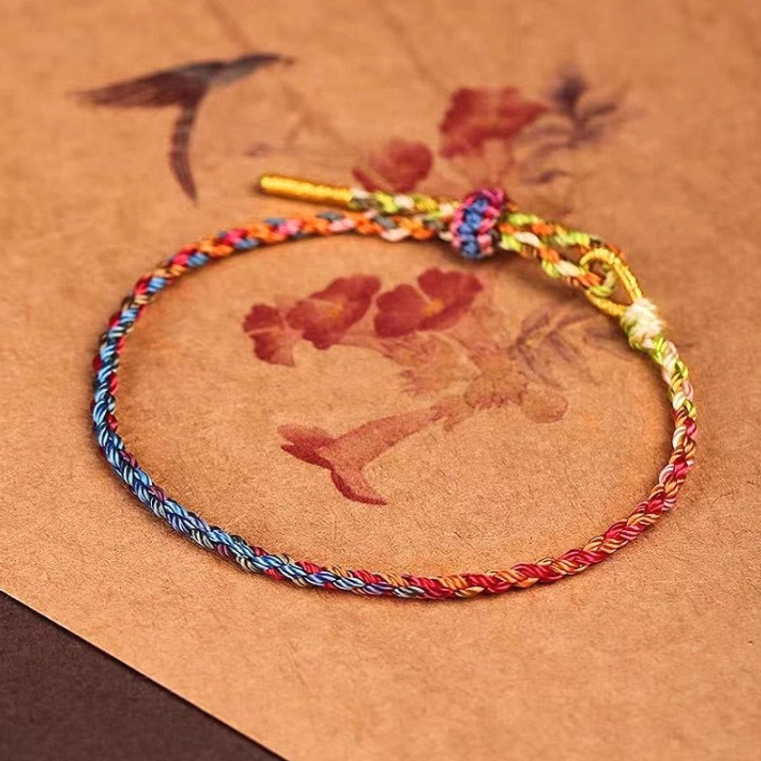 Colorful woven Buddhist protection bracelet with metal cord tips and sliding adjuster, vintage paper background