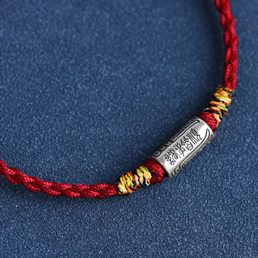 Sterling silver Buddhist string bracelet with engraved charm and woven rope, showing natural craftsmanship details and quality materials