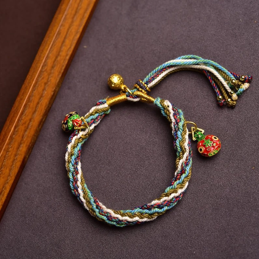 Blue and white Buddhist string bracelet with cloisonné Swallowing Beast charms and gold accents side view