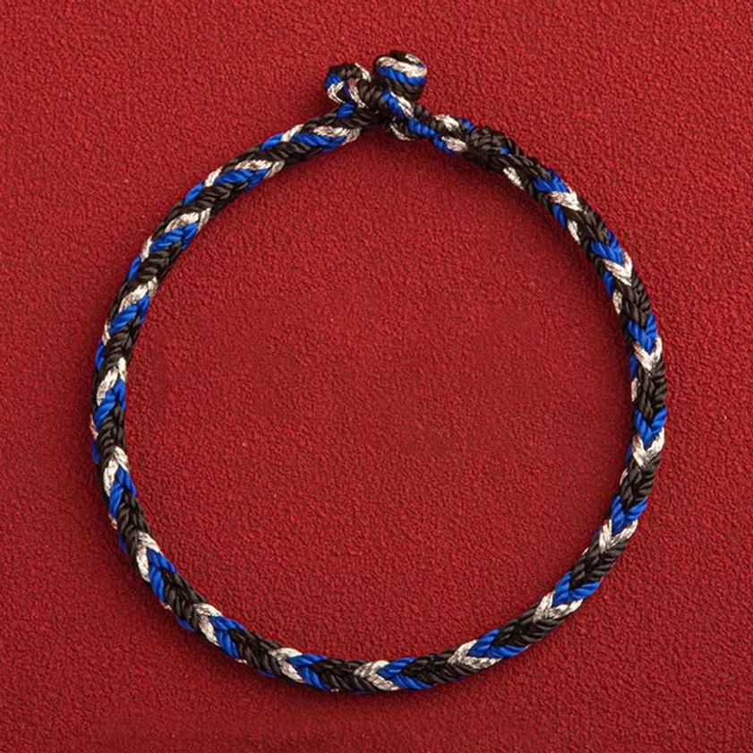 Close-up of braided Buddhist prosperity bracelet with vibrant tri-color weave and traditional knot closure