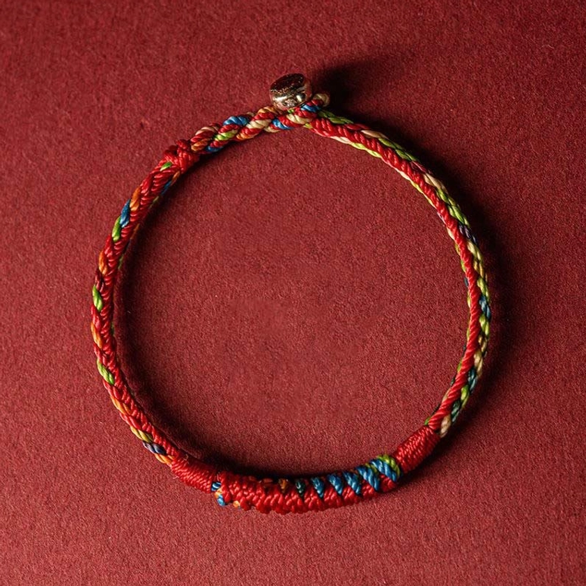 Handcrafted five-color Buddhist bracelet with metal toggle clasp, front flat lay showing braided cord details