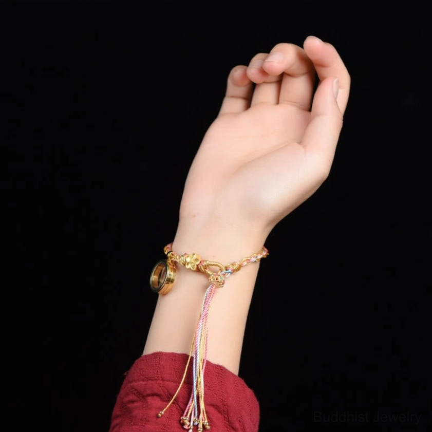 Buddhist lucky braided string bracelet worn on wrist - multicolor braided design with metal charm and long hanging tassel