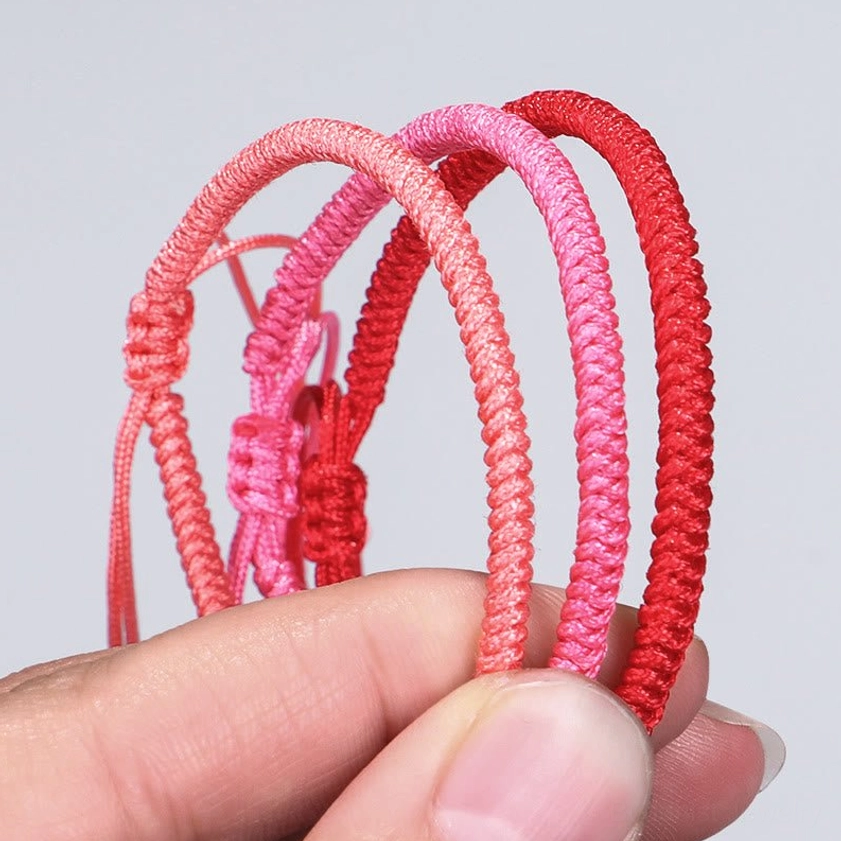 Layered Buddhist string bracelets in complementary red tones, demonstrating wearable stacking style for enhanced spiritual energy
