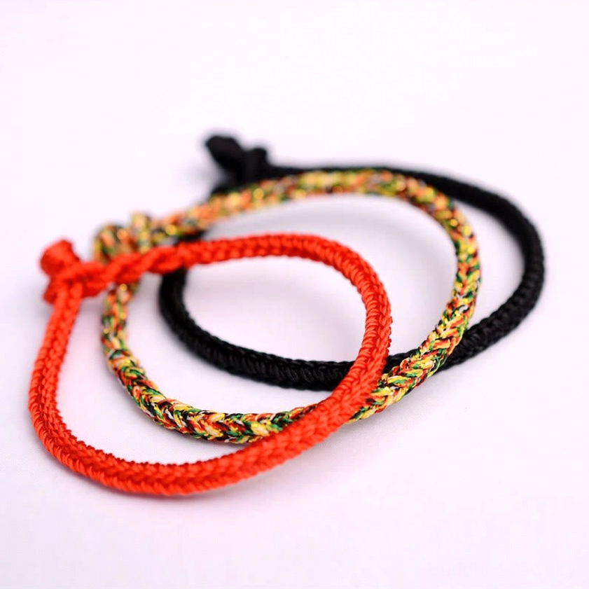 Three handmade Buddhist peace knot bracelets displayed flat showing red, black, and colorful woven styles side-by-side