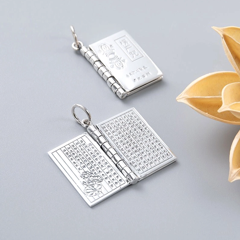 Open hinged silver Buddhist sutra book pendant showing full engraved mantra text on inner pages with polished finish