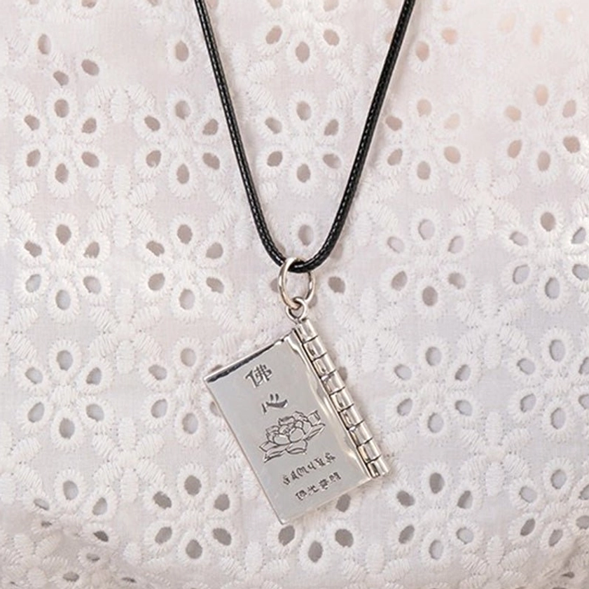 Silver Buddhist sutra book pendant with engraved lotus and Buddhist text on hinged book design with leather cord