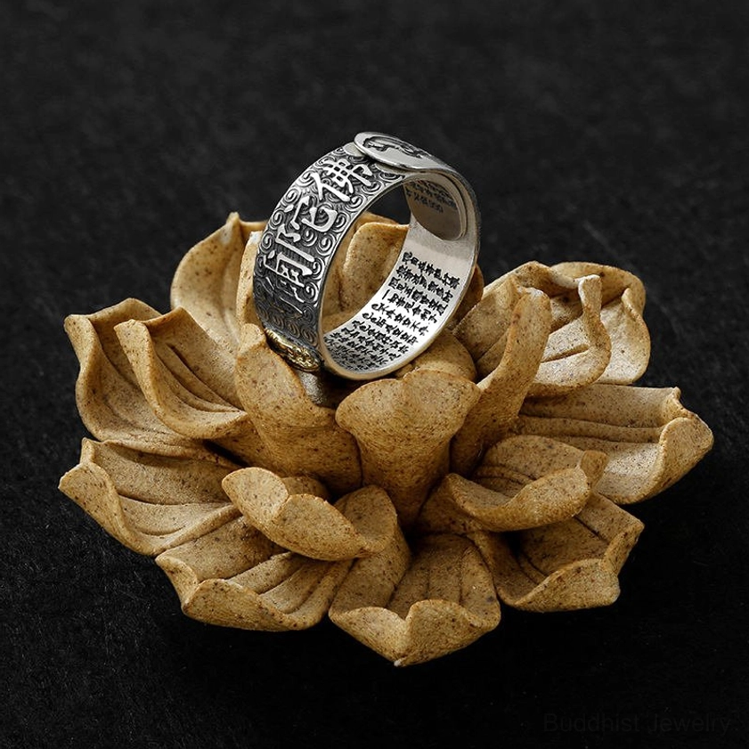 Buddhist sutra adjustable ring with close-up view of engraved sutras on inner and outer band, vintage silver finish displayed on wooden lotus ornament with dark background