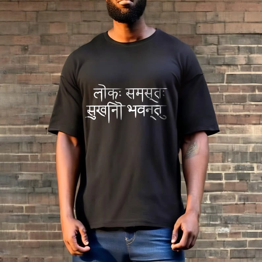 Man wearing black Sanskrit happiness T-shirt with white print paired with denim jeans against brick wall background