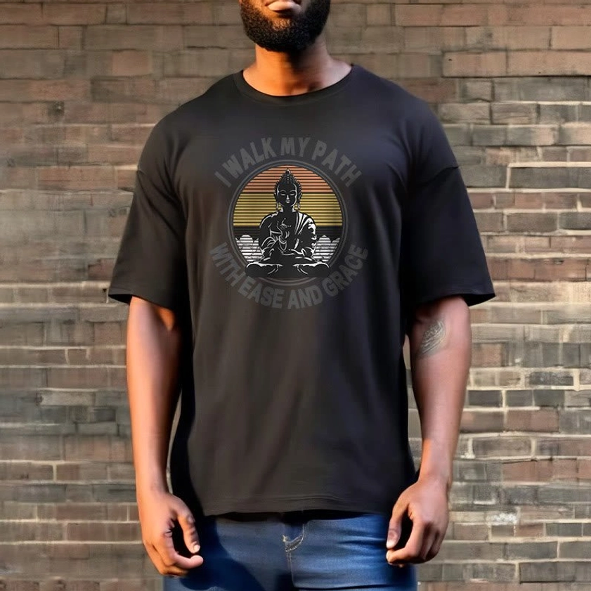 Man wearing charcoal grey Buddhist t-shirt with ease and grace print blue jeans brick wall