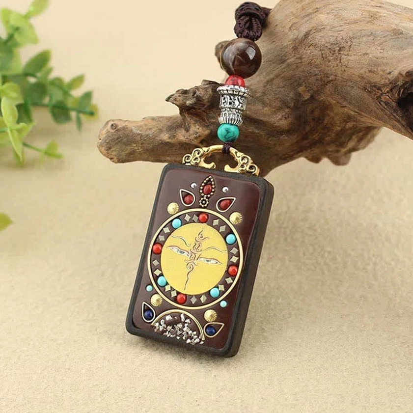 Authentic Buddhist Thangka ebony pendant necklace product photography, top-down flat lay showing full necklace with braided cord on neutral background
