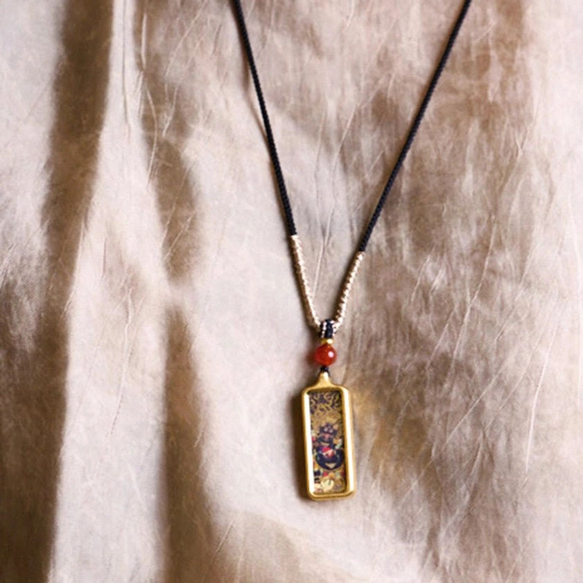 Full Buddhist thangka pendant necklace with mixed black and silver woven cord, small thangka pendant and red accent bead on linen fabric backdrop