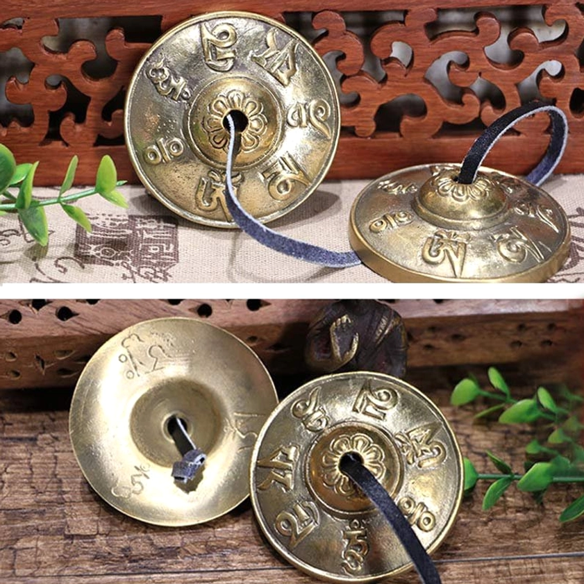 Tingsha bells with om mani padme hum engravings displayed on wooden table with Buddhist decor