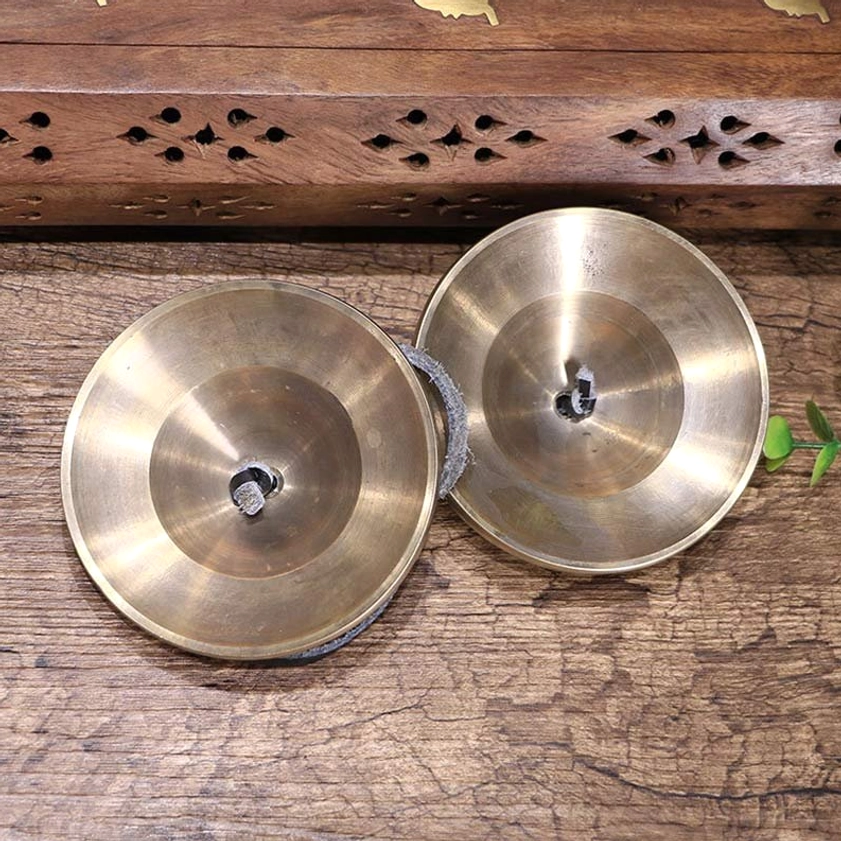 Back side view of pair Buddhist tingsha bells showing unfinished bronze finish, smooth flat surfaces and central hanging holes