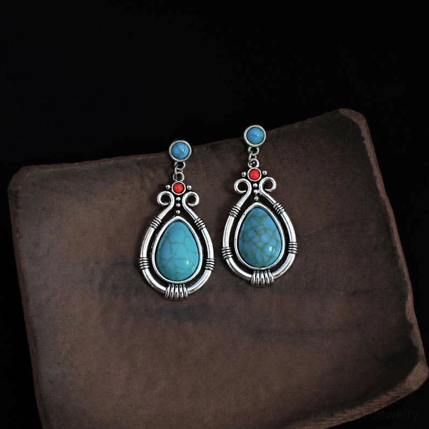 Handmade turquoise drop earrings pair displayed on wooden tray showing ethnic Buddhist jewelry design