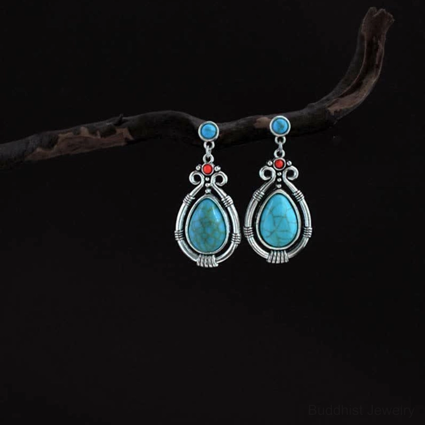 Vintage style turquoise earrings with veined stone wrapped in silver filigree on dark background