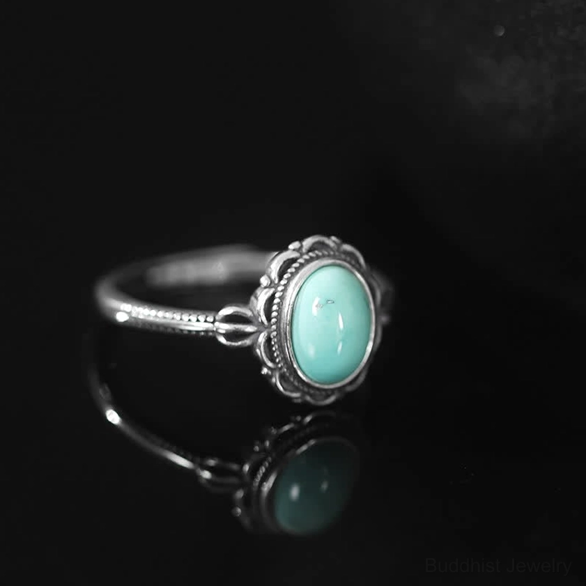 Front three-quarter view of sterling silver turquoise Buddhist ring with mirror reflection