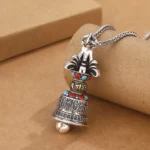 Buddhist Vajra Bell pendant necklace left side view with vintage silver finish and colored gemstone inlays on kraft paper background