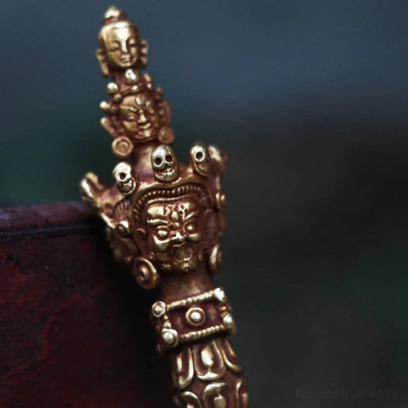 Intricate front close-up of handmade Vajra Dorje with wrathful Buddhist deity carvings, ornate bands, and relief texture on handle