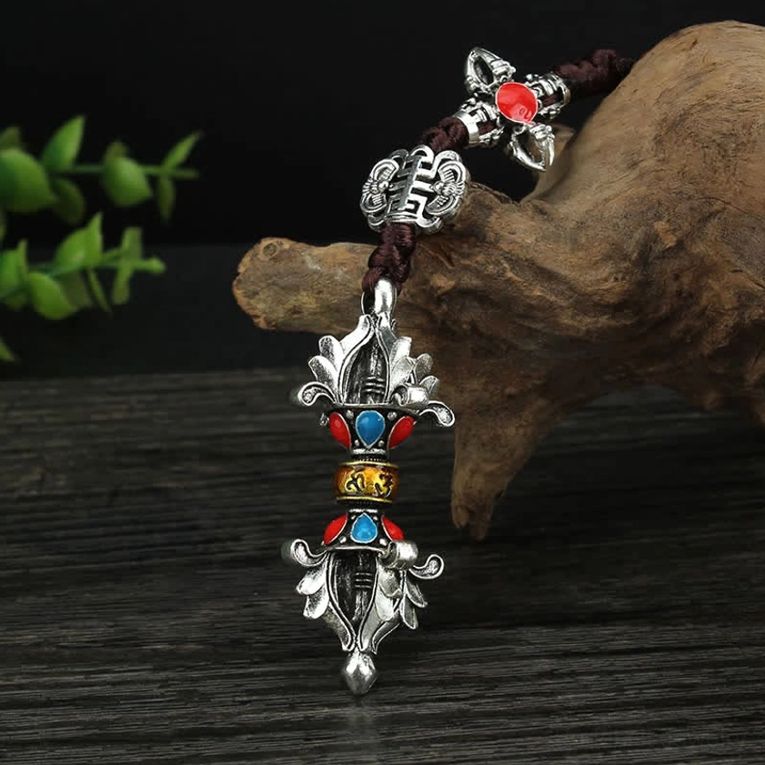 Tibetan Buddhist vajra hanging ornament with silver tone, red-blue gemstone accents, lotus and vajra decorations, and braided rope