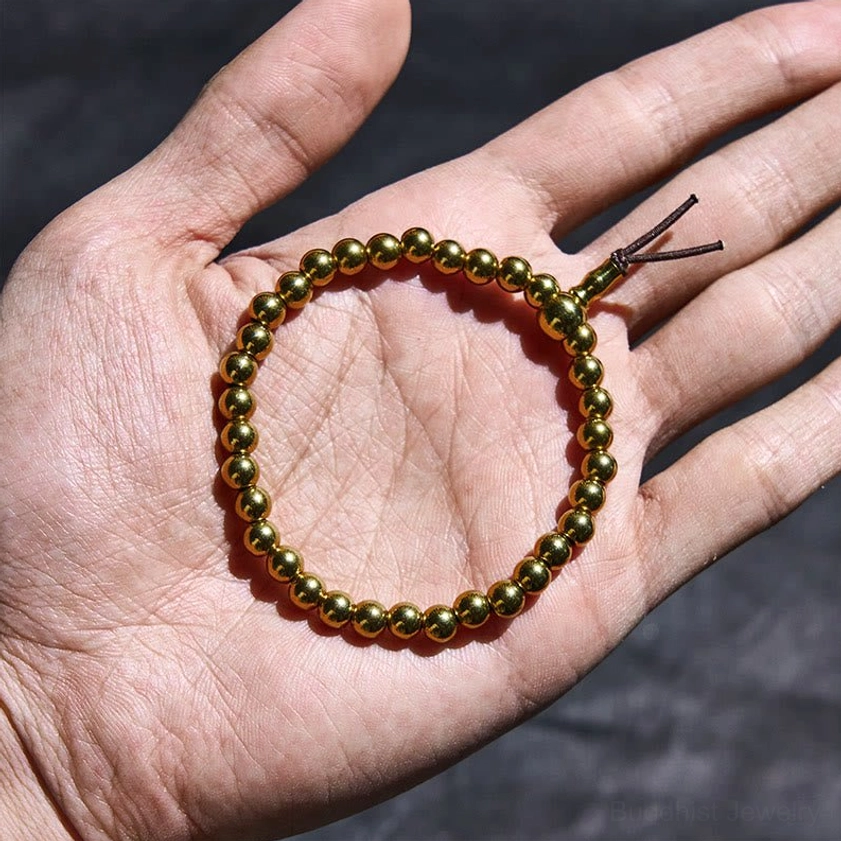 Compact copper brass beads with brown leather cord held in human hand for size reference
