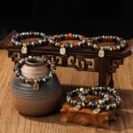 Collection of handcrafted Buddhist wealth goddess bracelets with multicolor Liuli glass beads and gold accents, displayed on traditional wooden table