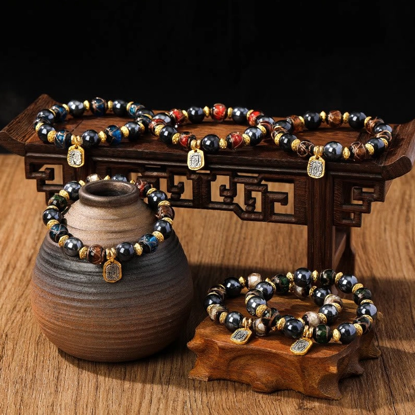 Collection of handcrafted Buddhist wealth goddess bracelets with multicolor Liuli glass beads and gold accents, displayed on traditional wooden table