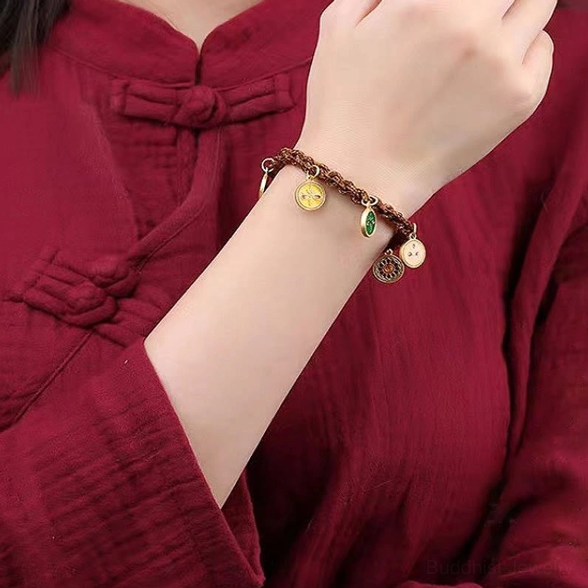 Wealth deity bracelet worn on wrist with traditional red clothing - close-up detail of gold-toned charms