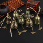 Antique bronze Buddhist wind chime bell with carved fish pendant on Chinese style tea set display