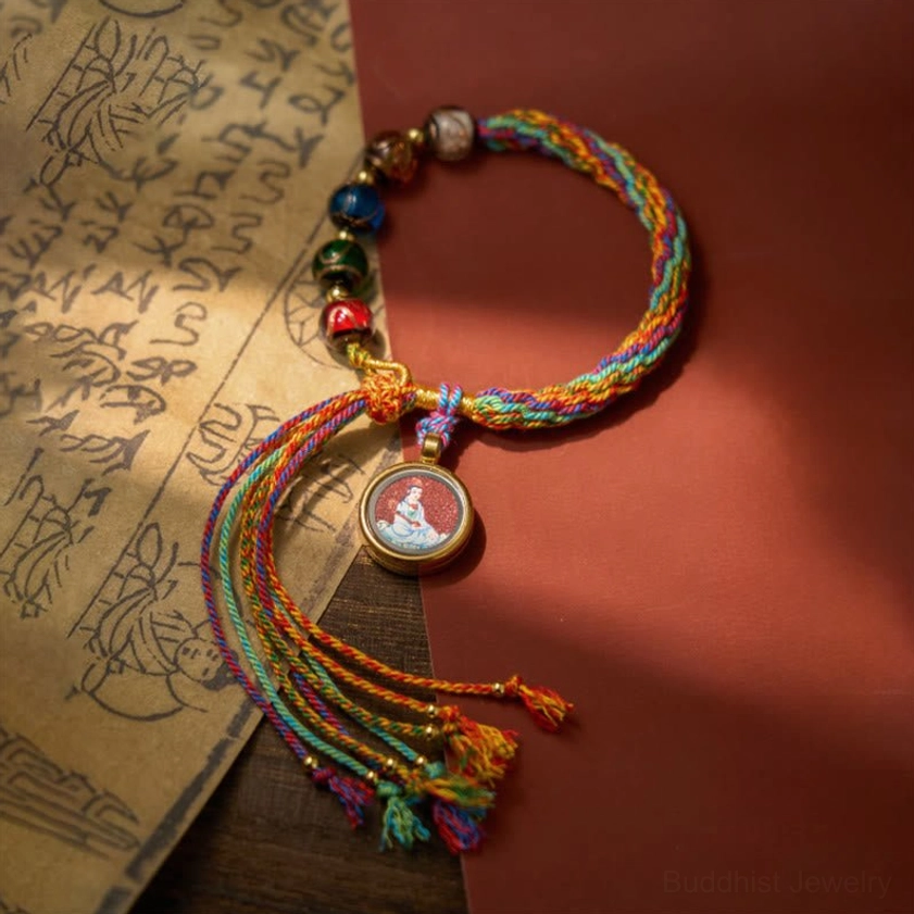 Buddhist zodiac natal Buddha bracelet on ancient Chinese script paper background, showing long decorative tassel ends and colorful woven rope design