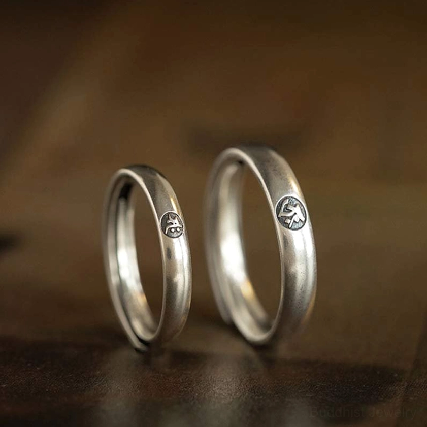 Pair of matching 925 sterling silver Buddhist zodiac couple rings with embossed zodiac emblems, flat lay view