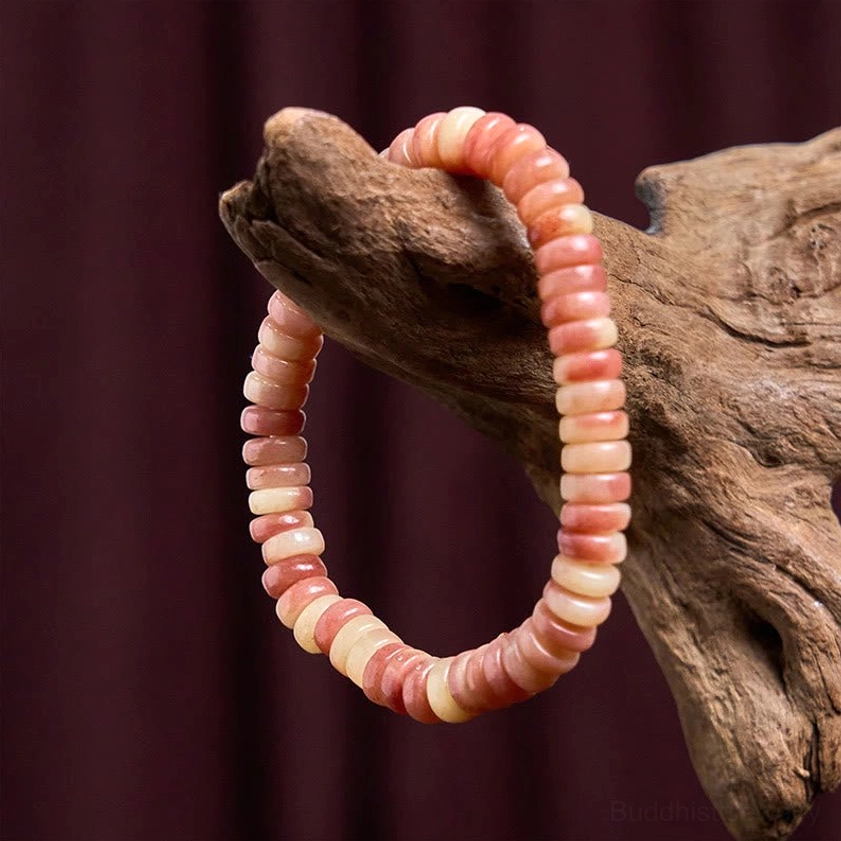 Camel bone beaded bracelet with gradient pink to cream disc beads on driftwood and dark purple backdrop, Buddhist spiritual jewelry