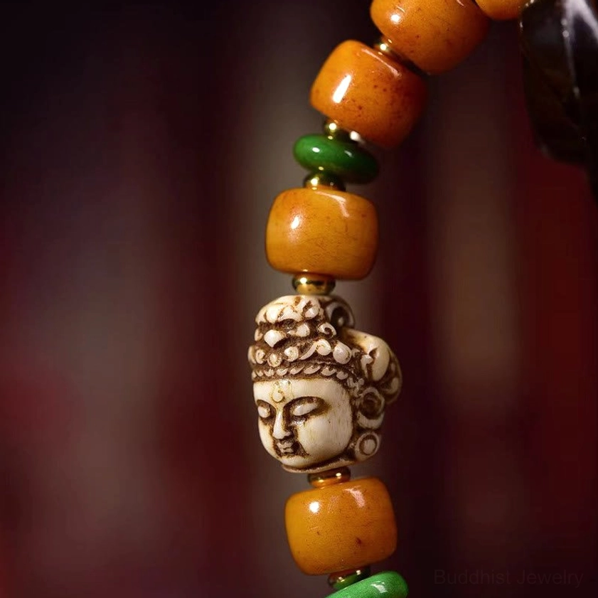 Macro close-up of bracelet components highlighting multi-faceted carved Buddha head, premium barrel-shaped camel bone beads, and green jade spacer beads with artisan details