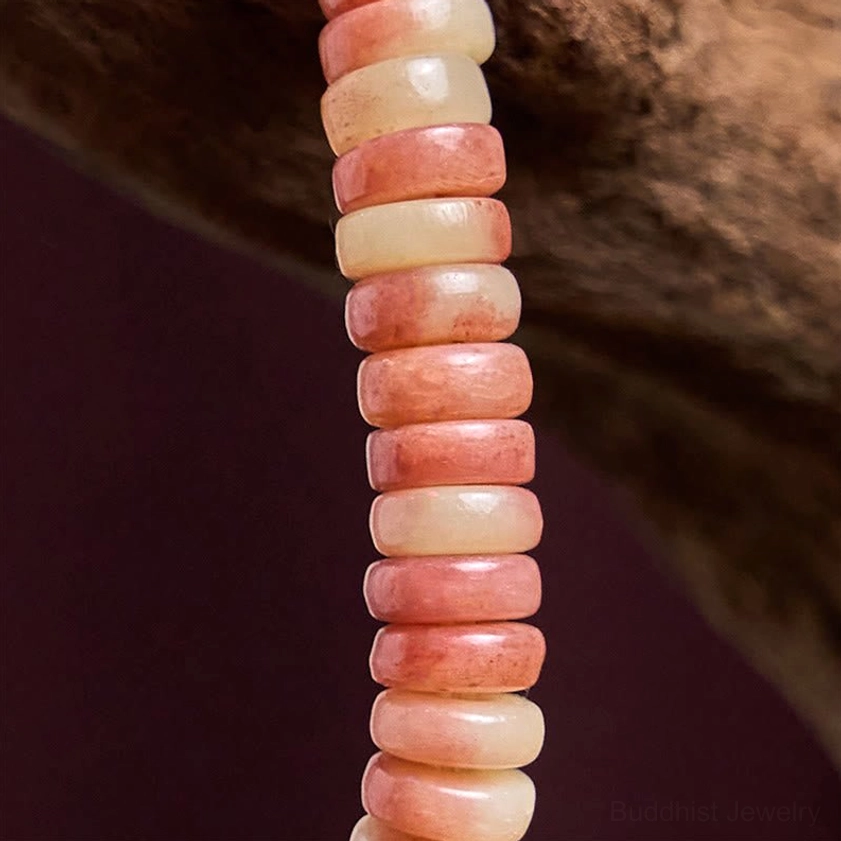 Close-up detail of stacked polished camel bone disc beads showing gradient pink and creamy natural tones and smooth matte texture