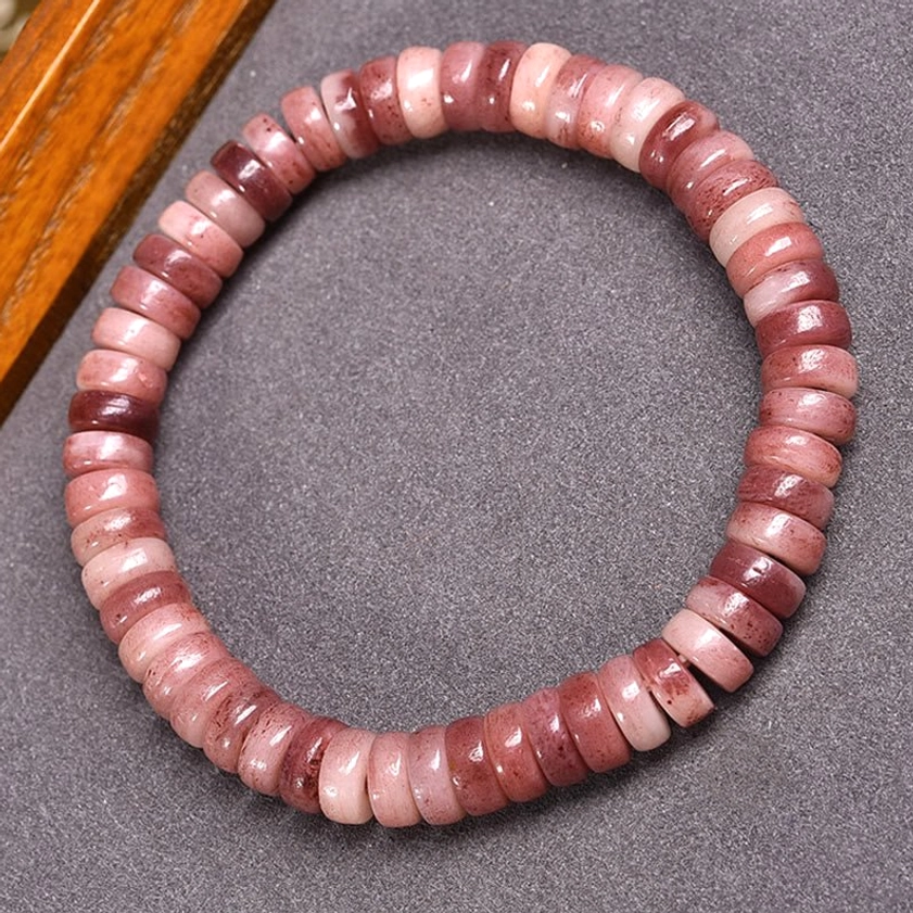 Natural camel bone disc beads bracelet with gradient reddish-purple to light pink coloring, handcrafted Buddhist protection bracelet, flat lay view on fabric