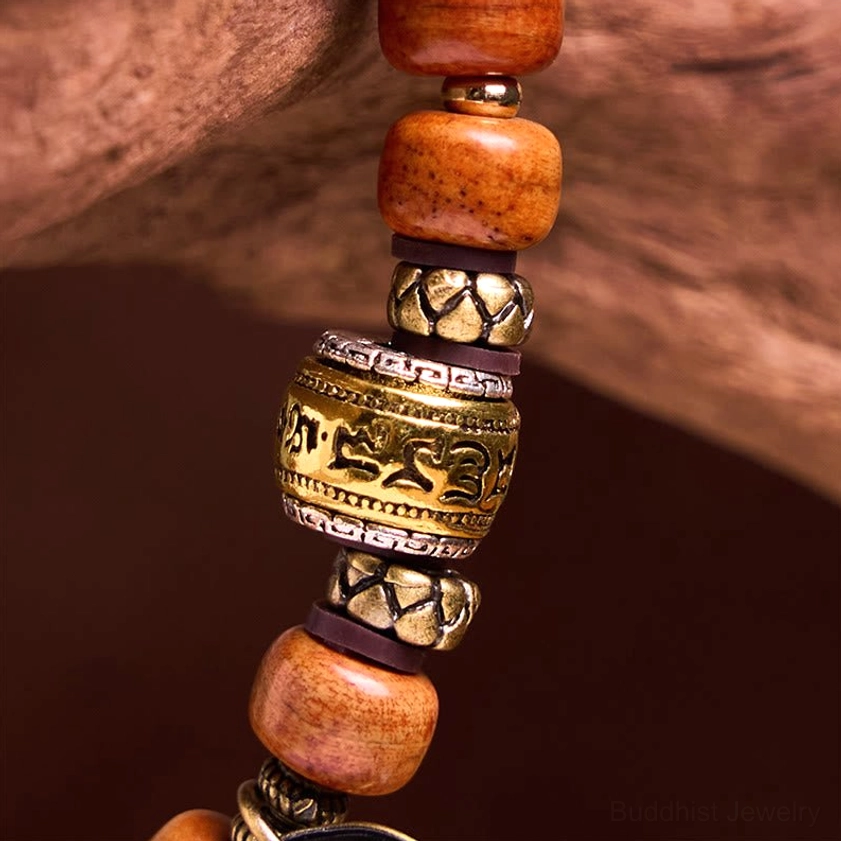 Macro close-up of OM bracelet spacer and barrel bead details, highlighting carved metal accents and warm brown camel bone craftsmanship