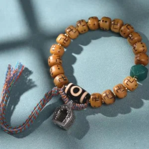 Camel bone Buddhist prayer bracelet with black Dzi bead, swastika charm, and woven tassel on blue background