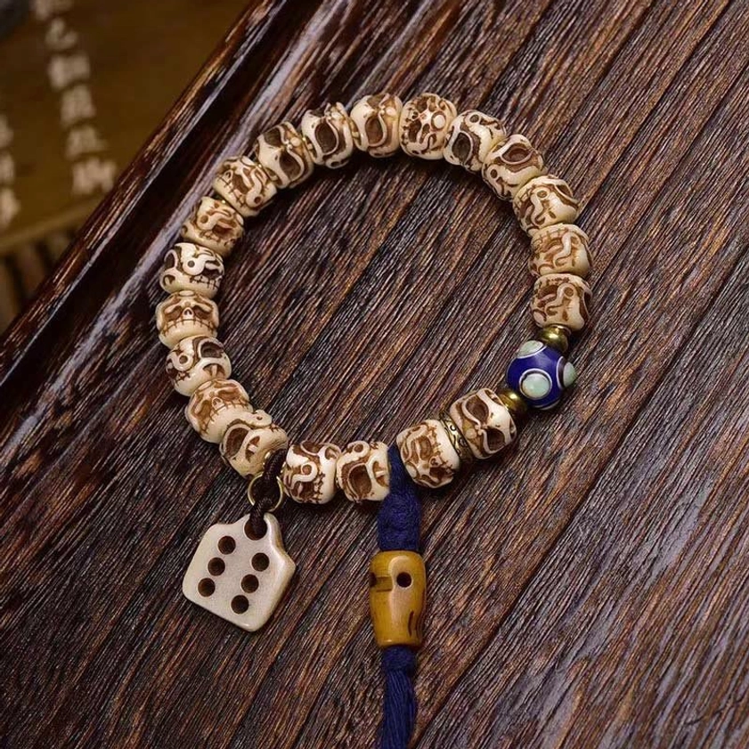 Camel bone dice pendant bracelet showing blue enamel detail and wooden toggle clasp mechanism