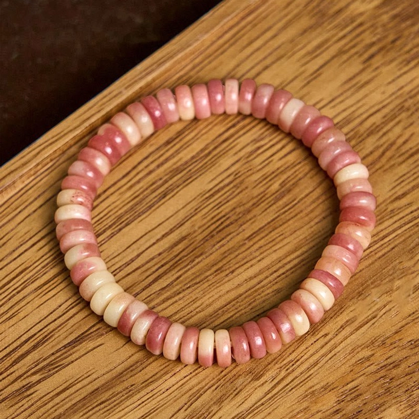 Polished camel bone beaded bracelet featuring warm pink to cream natural color gradient, elastic cord design on wooden surface