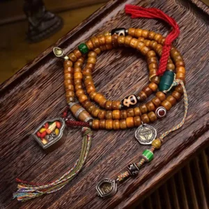 108 bead camel bone Buddhist prayer mala flat lay featuring natural bone beads, dzi stones, agate accents, metal charms, and woven tassel on vintage wooden surface