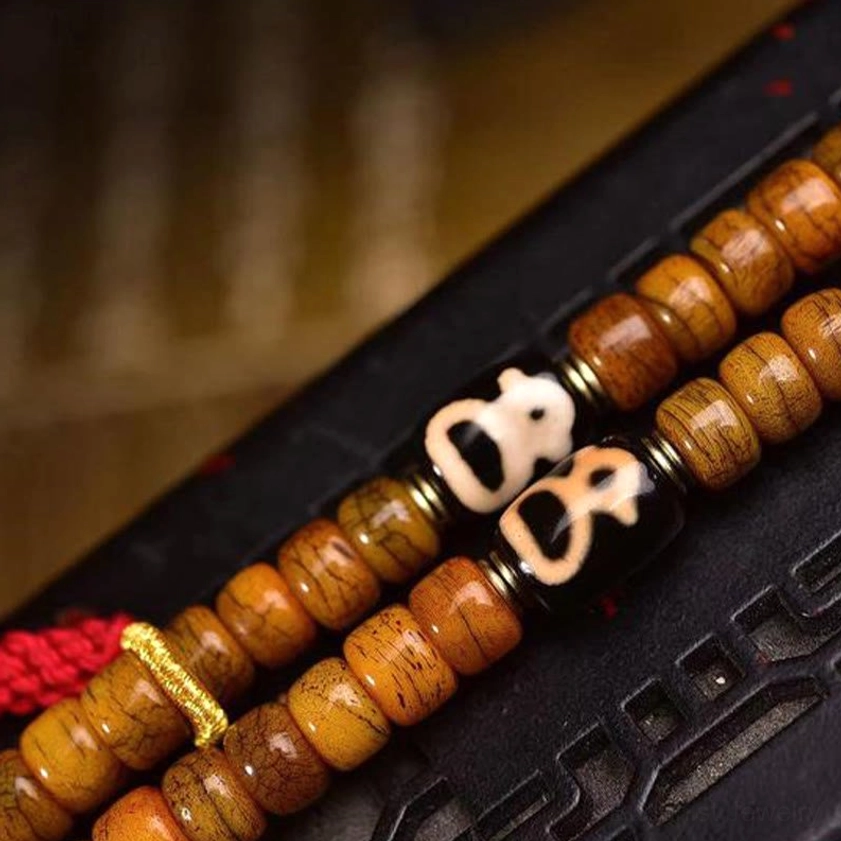 Close-up macro photography of camel bone mala beads showing natural striated bone texture, skull-shaped metal spacers, and sacred dzi bead details