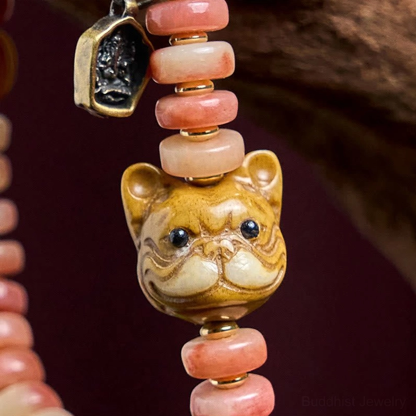 Close-up detail of Buddhist camel bone bracelet showing pink disc beads, carved bulldog charm, and metal tag pendant texture