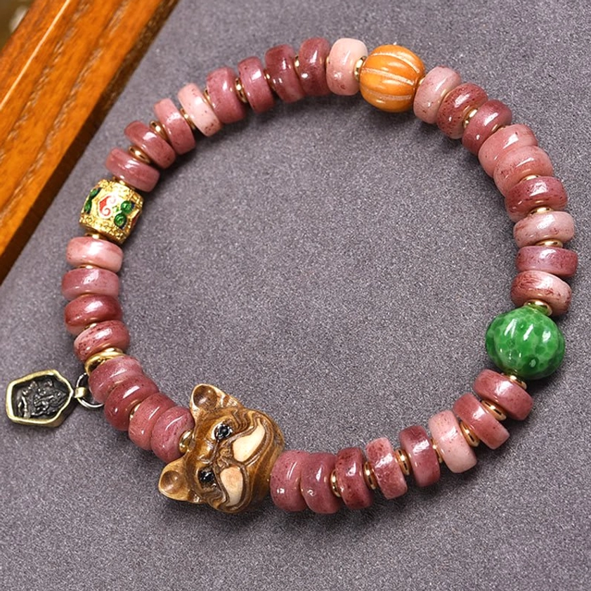 Natural camel bone pug charm beaded bracelet with gradient pink disc beads, green stone, and metal tag pendant - flat lay top view