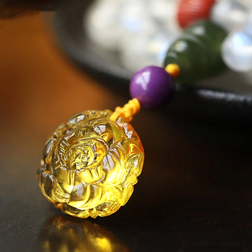 Hand-carved amber lotus pendant macro close-up, golden floral carving matched with purple and jade beads