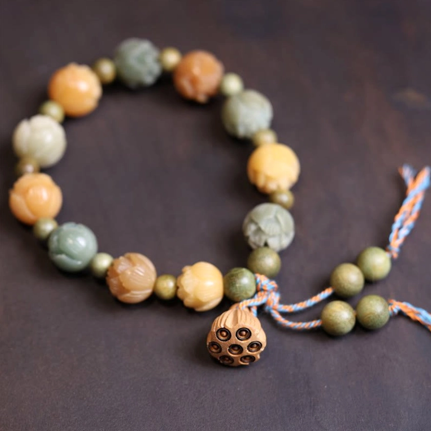 Handcrafted bodhi seed beaded bracelet with carved lotus beads and wooden pendant on dark wooden background