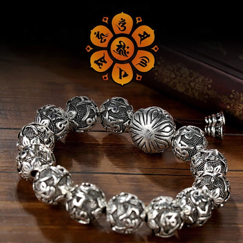 Mantra carved alloy beads bracelet with central lotus guru bead and aged silver finish on wooden table with Buddhist emblem