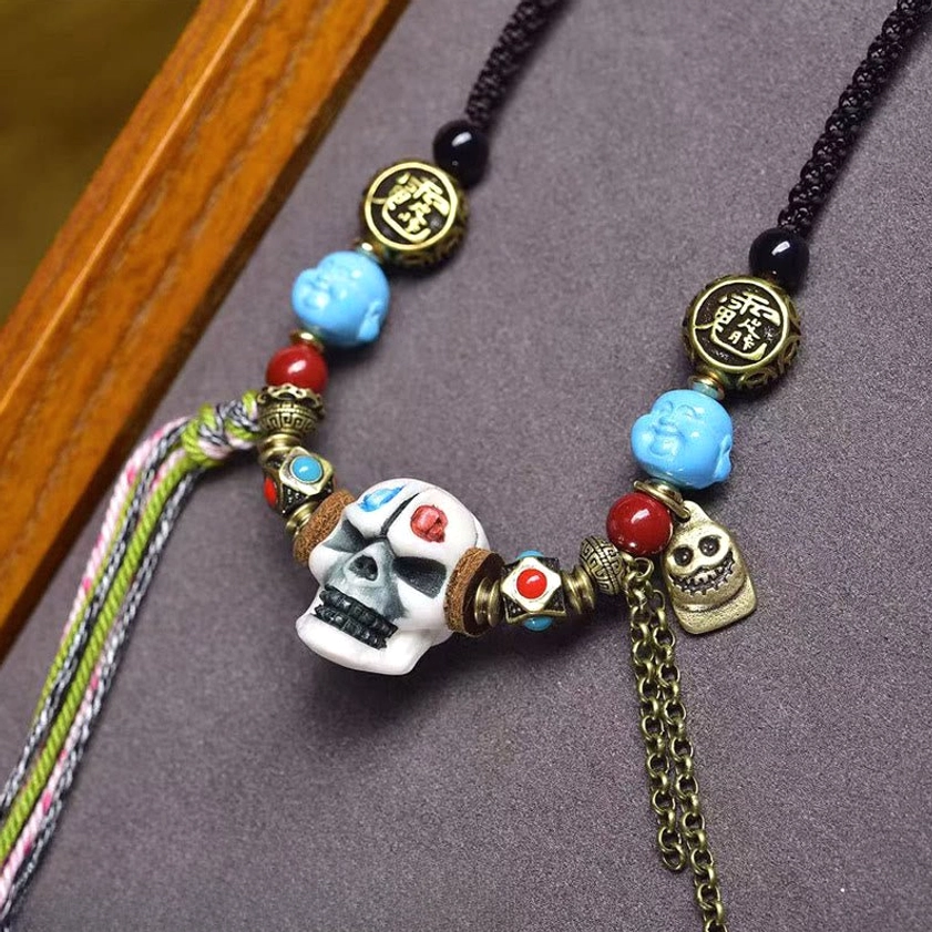 Detailed carved bone skull pendant Buddhist necklace with Chinese character metal beads, turquoise stones, and multicolored woven tassels
